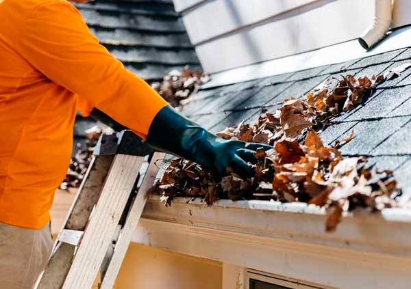 Operator removing leaves from a roof gutter