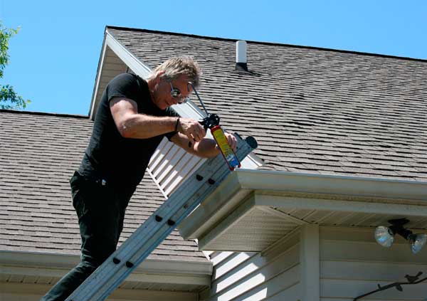 Operator applying silicone to water seal a gutter