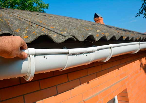 White plastic guttering being fixed