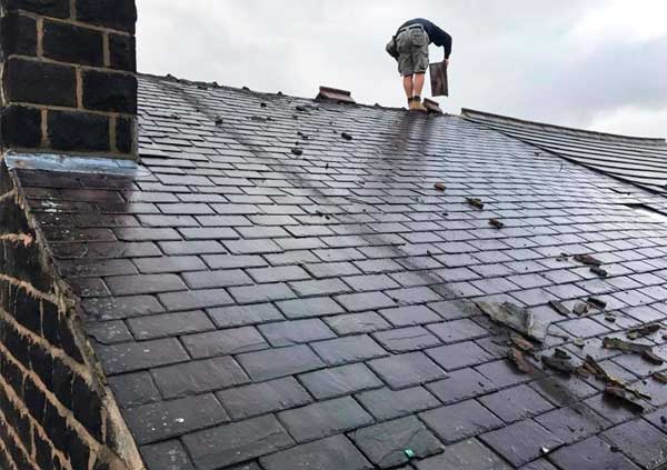 Operator repairing water leaks in a slate roof