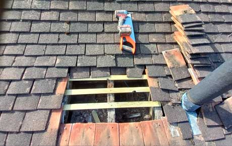 Operator replacing tiles form a roof