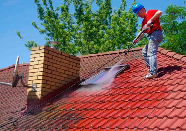 Operator cleaning with pressured water a red tiles roof