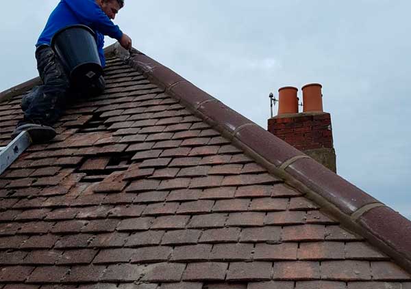 Operator replacing brown tiles on a roof