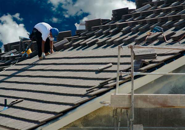 Operator tiling a roof with black tiles