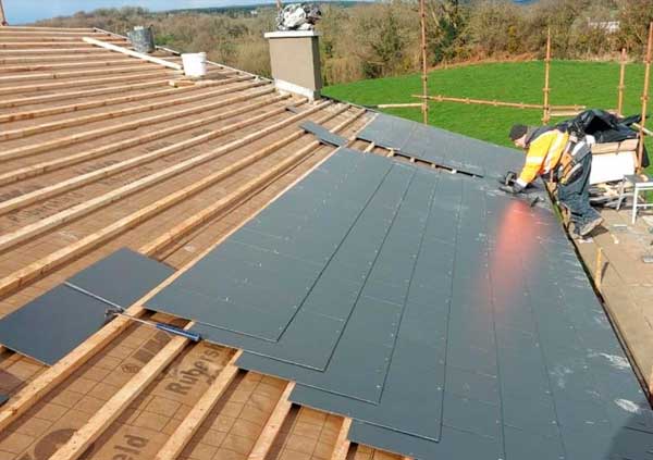 Operator tiling a countryside roof with black slates